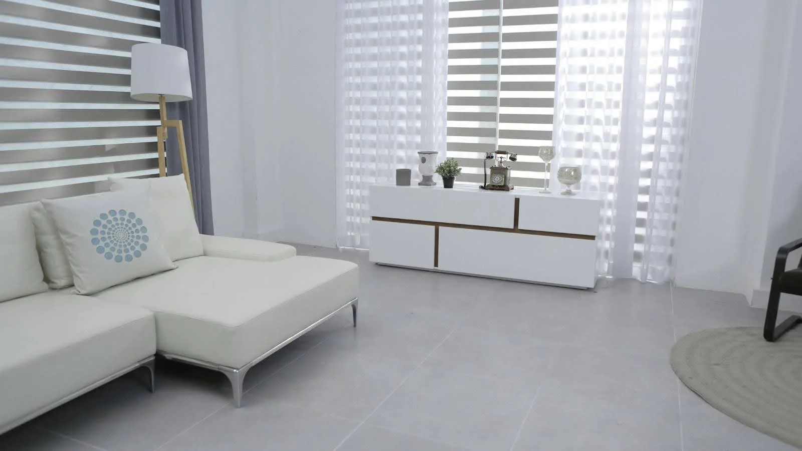 picture of a spacious white room with large windows a modern low profile sofa and a white sideboard decorated with a vintage style telephone