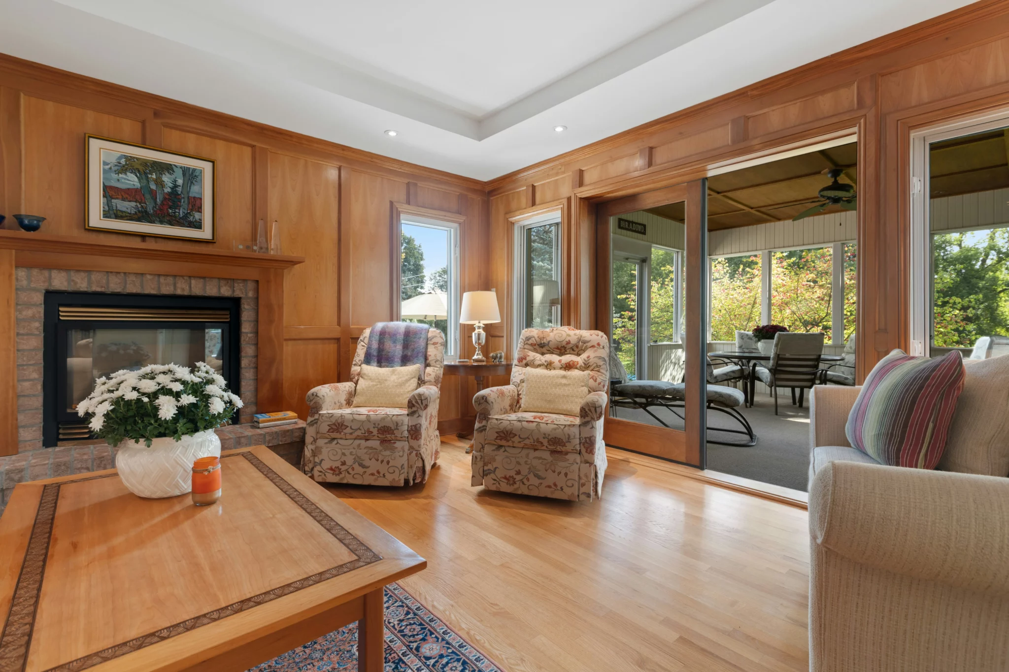 photo of a room addition with wood walls vintage furniture and a brick fireplace