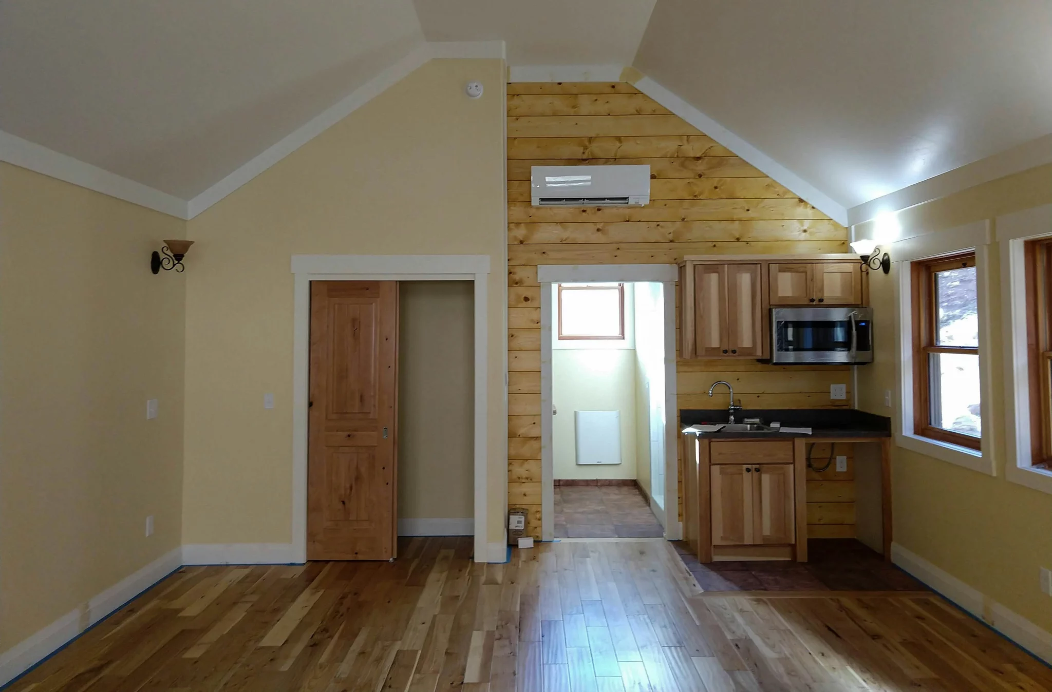 photo of a renovated room with a built in kitchen and wood structures to display room addition ideas